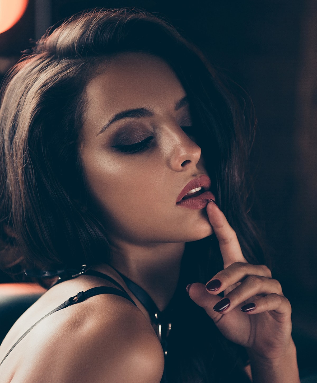 Woman with finger on lips, dramatic lighting.