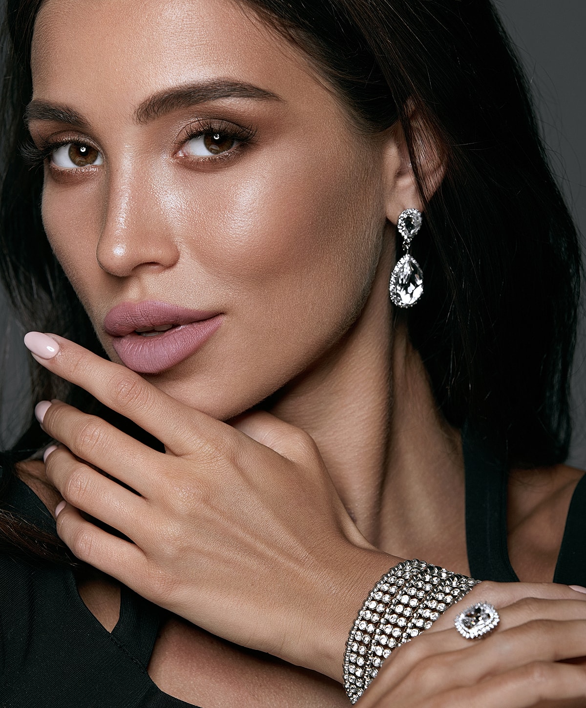 Woman showcasing elegant jewelry and makeup.