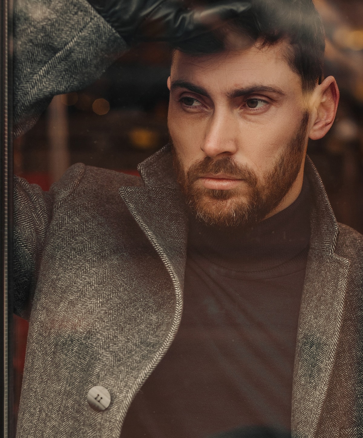Man in stylish coat looking out a window.