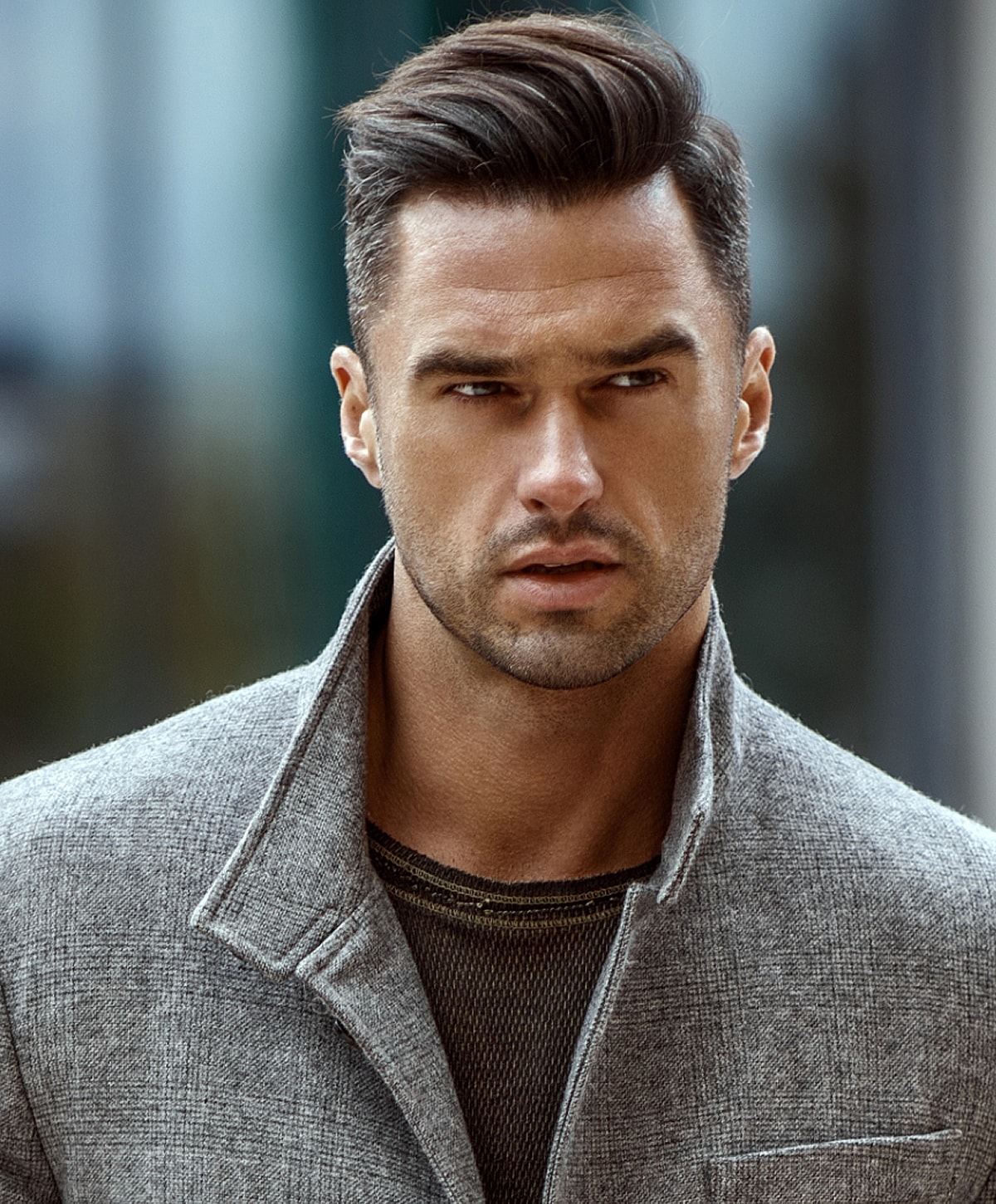 Man with stylish haircut wearing gray coat.