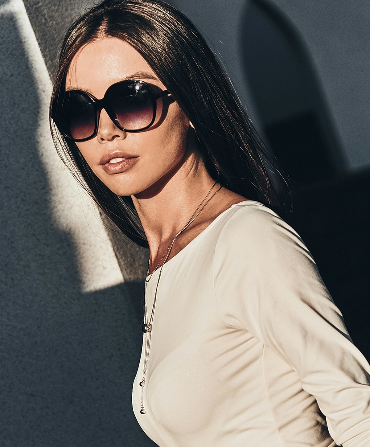 Woman in sunglasses, stylish outfit, natural light.