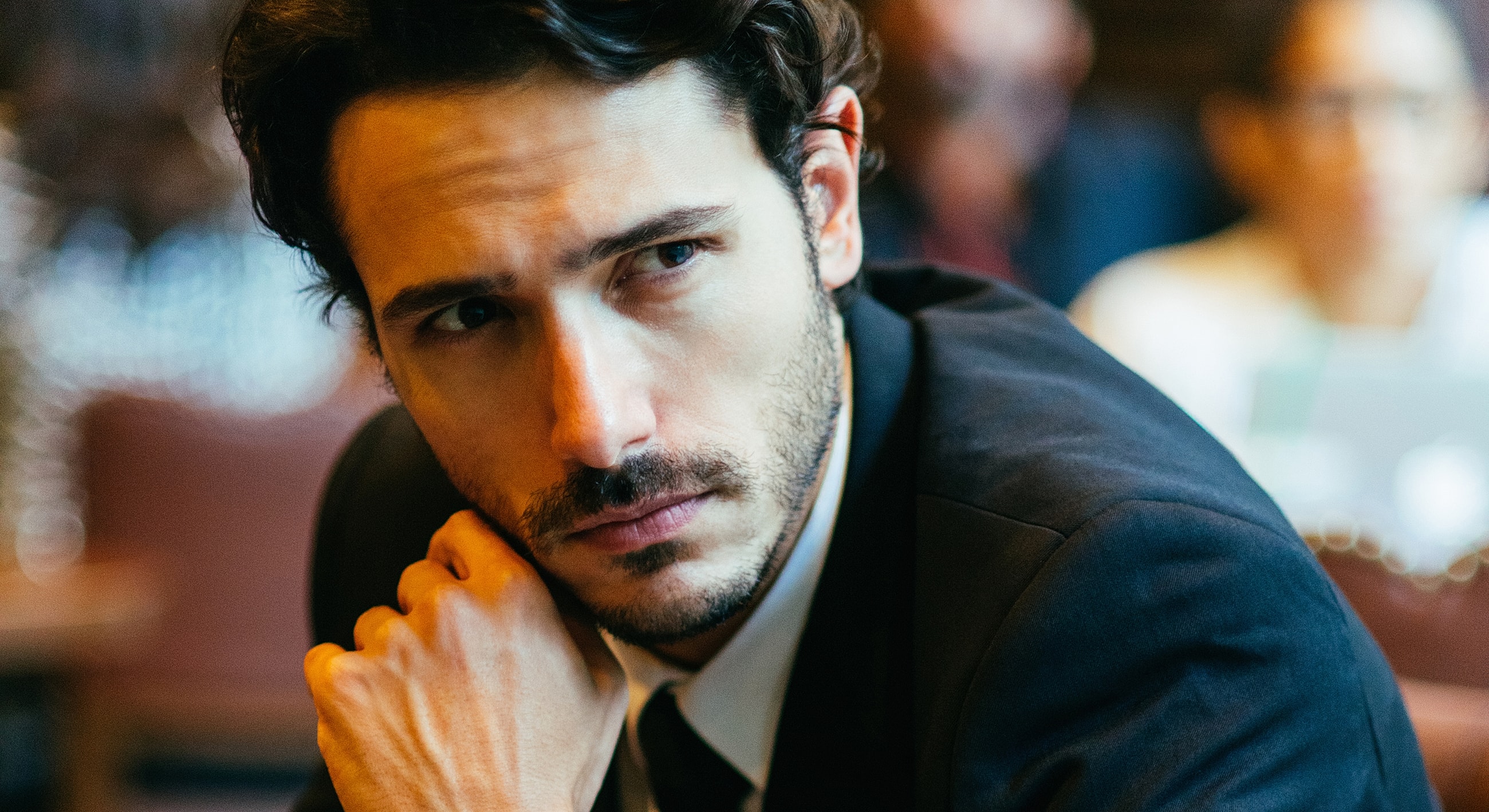 Man in suit looking thoughtfully with hand on chin.