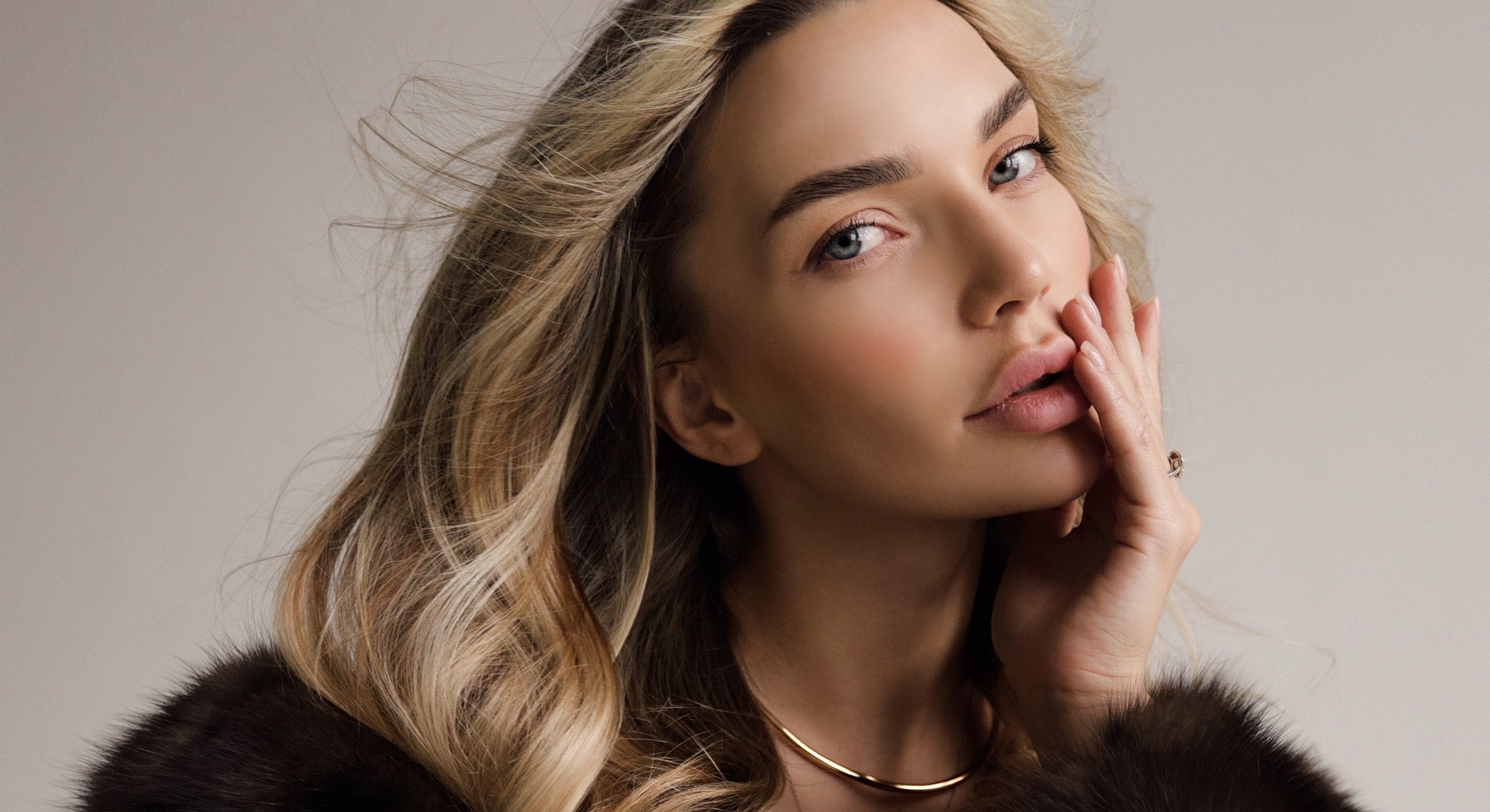 Woman touching her face with flowing hair.